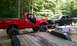 1994 Ford F-250 - A red 1994 Ford F-250 pickup truck with a lifted suspension and large off-road tires is parked next to a black pickup truck.
