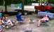 1994 Ford F-250 - A lifted red pickup truck is parked at a campsite with a trailer and two women relaxing.