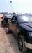 1994 Ford F-250 - Two trucks are parked on a sandy terrain, one black and one red, both with flags attached.