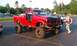 1994 Ford F-250 - Modified red pickup truck with large tires and no doors parked in a lot.