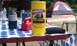 1994 Ford F-250 - A picnic table is set up with camping supplies, including a propane tank and a large yellow tin of honey liqueur.