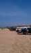 1994 Ford F-250 - Trucks are parked on a sandy beach with people standing around them and red flags in the background.