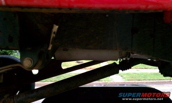 Underside view of a truck's frame, showing suspension parts and a shock absorber