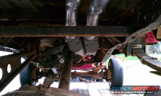 Underside view of a truck's frame, showing dual exhaust pipes and suspension components