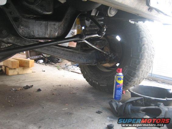 close-up of vehicle's front suspension and steering linkage with a can of WD-40 nearby
