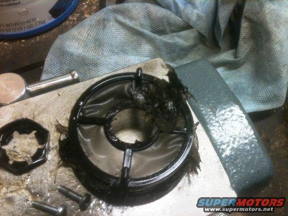 Dirty oil filter housing with debris and screws on a workbench