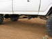1995 Ford Bronco - Side view of a white pickup truck's rear suspension system and large tires.