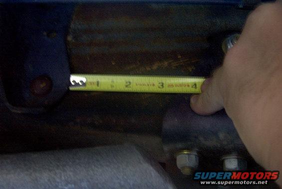 Measuring suspension component with a tape measure showing 3 inches