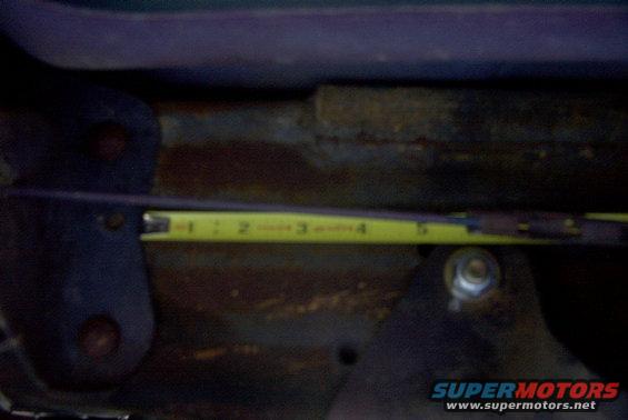 Yellow measuring tape showing inches on a rusty metal surface with bolts