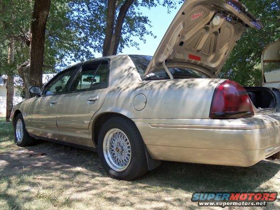 gold sedan, trunk open, showing aftermarket lights inside. Aftermarket wheels visible