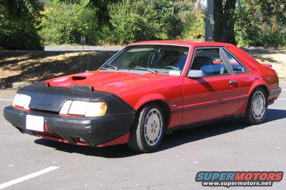Red coupe with black car bra and hood scoop, 3/4 front view