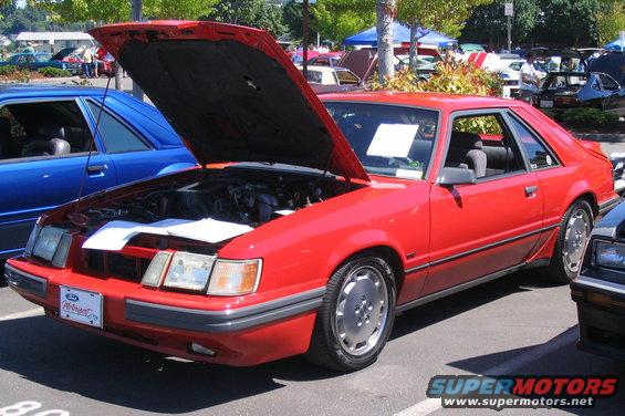 Red 1982 Ford Mustang GT coupe with hood open, parked next to a blue car