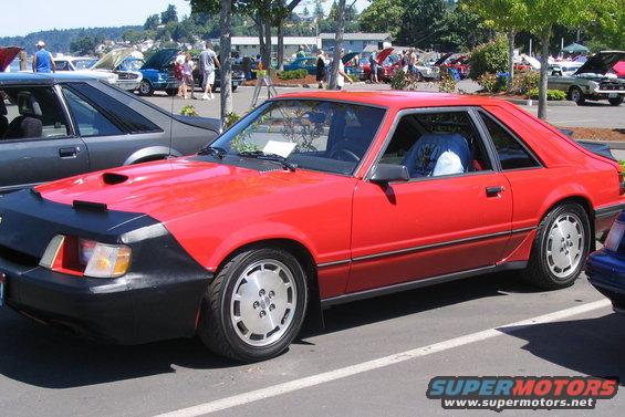 Red coupe with a black car bra and silver wheels, seen from the front 3/4 angle