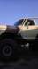 1989 Ford Bronco - A lifted 1978 Ford Bronco with custom paint and large off-road tires is parked under a clear blue sky.