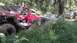 1989 Ford Bronco - Several off-road vehicles are parked in a wooded area, with the closest one being a modified red truck.