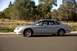 1998 Ford Taurus - Side view of a silver sedan parked on the side of a road with trees and vegetation in the background.