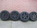 2010 Ford Fusion - A set of four black alloy wheels and tires are displayed in front of a brick wall.