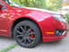 2010 Ford Fusion - Close-up of the front passenger side of a red sedan, highlighting its wheel and fender.