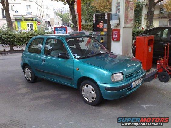 Teal hatchback car with a license plate reading 247LOC75, parked at a gas station