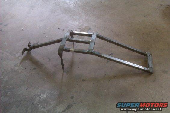 Metal luggage rack with welded joints and mounting brackets, resting on a concrete floor