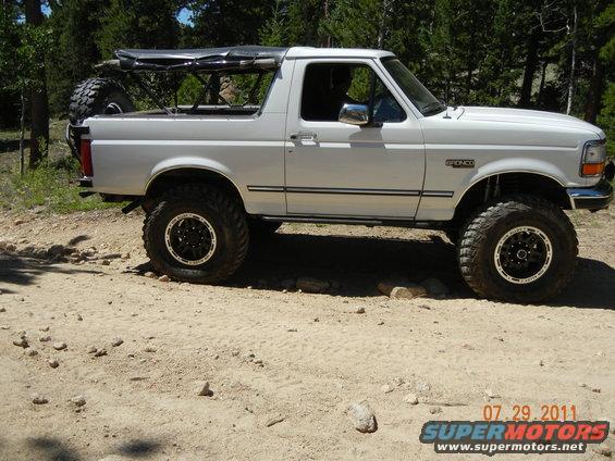 white Ford Bronco with lifted suspension and off-road tires, spare tire mounted on back