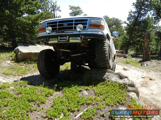 White Ford Bronco on rocks, front view, lifted suspension, off-road tires