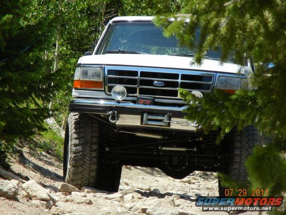 White 1996 Ford Bronco on rocky terrain, front view, with winch and aftermarket bumper