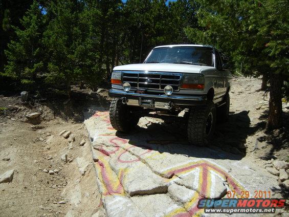 White Ford Bronco on a rocky trail, lifted with off-road tires