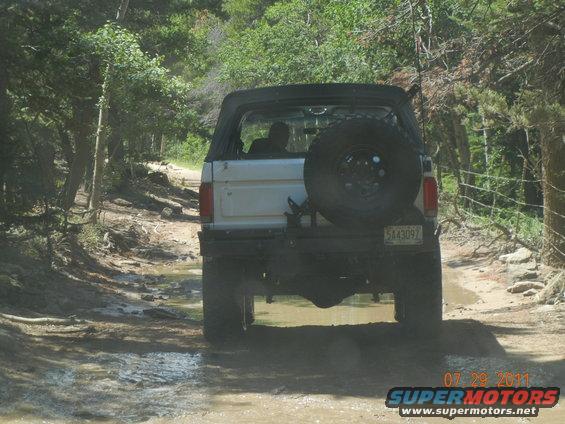 1992 Ford Bronco rear view on a muddy trail, spare tire mounted on back