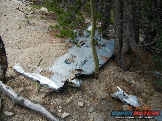 wreckage of an airplane wing and fuselage in a wooded area