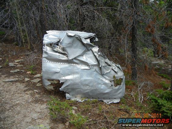 Wrecked aluminum vehicle body in forest, dented and torn