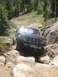 1995 Ford Bronco - 1995 Ford Bronco tackling a challenging off-road path with large rocks.