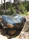 1995 Ford Bronco - A dark green Ford Bronco navigates a rocky trail, demonstrating its off-road capabilities.