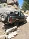 1995 Ford Bronco - A black Ford Bronco navigates a challenging rocky terrain on a sunny day.