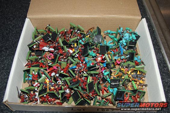 Box of assorted miniature figures, mostly red and green, with some blue figures