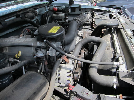 Engine bay with hoses, alternator, and air intake visible