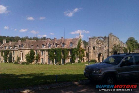 Silver Jeep Grand Cherokee parked in front of an old stone building with ivy
