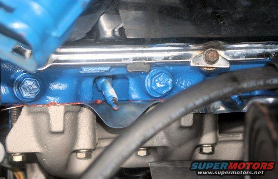 Engine part with blue paint and spark plug, SuperMotors.net logo