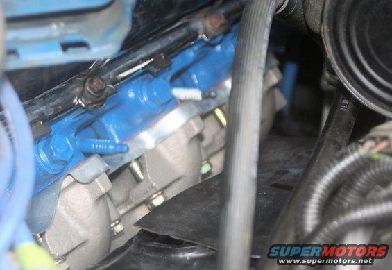 Close-up of blue painted engine manifold with hoses and bolts