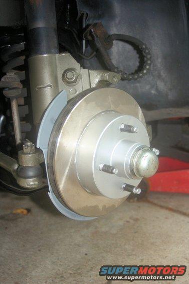 Close-up of a car's front brake rotor, caliper, and suspension components