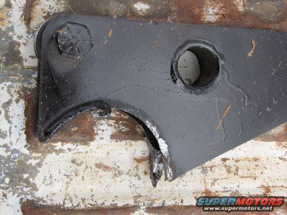 Black metal suspension part with a broken section and a large bolt