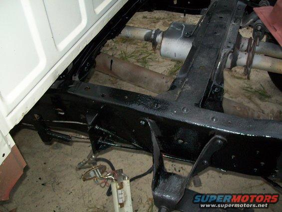 Close-up of a truck's frame, showing the exhaust system and fuel tank components