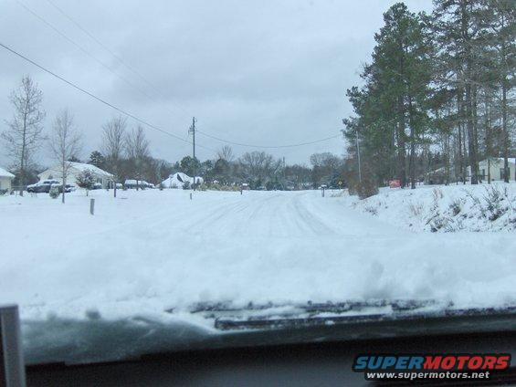 snowy road in a neighborhood with houses and trees