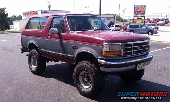 Red and gray Ford Bronco parked on asphalt, front grille visible