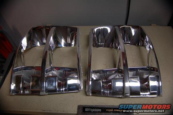 Two chrome headlight bezels, possibly for a truck, on a workbench
