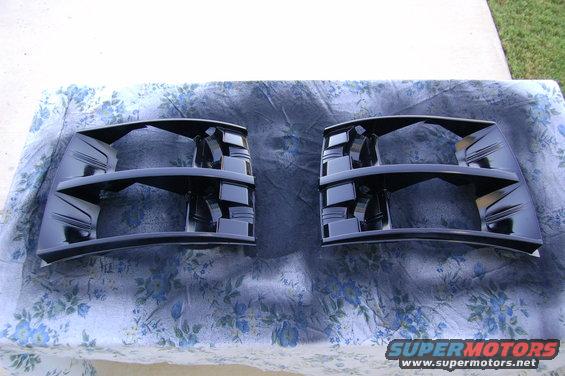 Two black headlight housings laid out on a patterned cloth