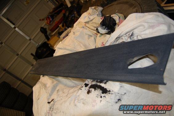 Dark gray plastic trim piece with a triangular cutout, resting on white cloth