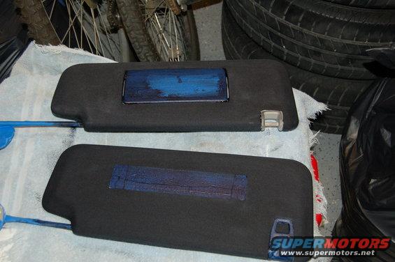 Two black sun visors with blue paint applied to a rectangular area