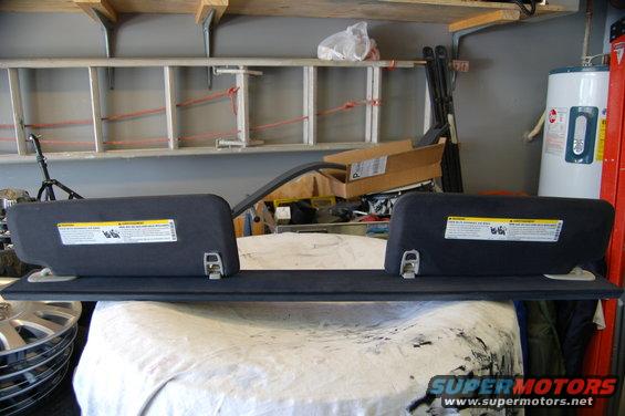 Two dark gray sun visors with warning labels attached, resting on a surface