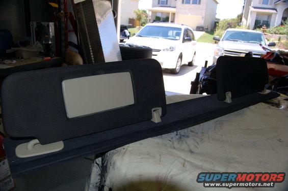 Dark gray fabric sun visor with a beige mirror panel and a long, dark gray trim piece with mounting clips